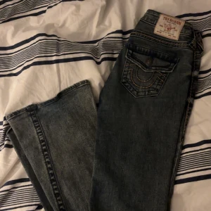 Mörkblå/grå  jeans från True Religion - Snygga mörkblå/grå jeans från True Religion med slitna detaljer och en klassisk femficksdesign. Jeansen har en knappgylf och kontrastsömmar som ger en cool look. Perfekta för en avslappnad stil. Storlek 24❤️pris kan diskuteras!