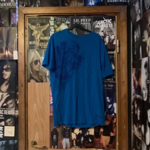 Blå t-shirt med tryck - Säljer en blå t-shirt med ett coolt tryck på framsidan. T-shirten har en normal passform och är kortärmad, perfekt för en avslappnad stil eller affliction/grisch. Storlek XL men sitter som en L.