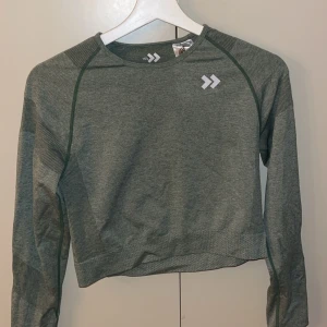 Grön långärmad tröja från 157 - Säljer en grön långärmad tröja från 157. Tröjan har en rund halsringning och är tillverkad i ett mjukt material med ribbade detaljer på ärmarna och nederkanten. Väldigt luftig 