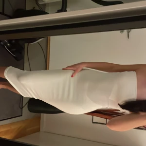 Vit axelbandslös klänning - Elegant vit axelbandslös klänning med en tight passform. Perfekt för en stilren look. Klänningen har en smickrande siluett och är knälång.