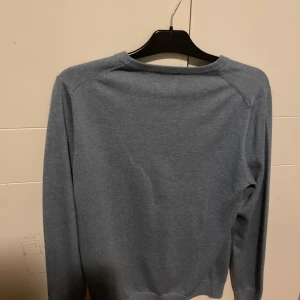 Blå tröja från bläck - Säljer en stilren blå tröja från Bläck. Tröjan har en klassisk rund hals och långa ärmar, perfekt för en avslappnad look. Den är tillverkad i ett mjukt material som känns skönt mot huden. Passar bra till jeans eller chinos. Skick 10/10 aldrig använd!