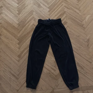 Svarta mjukisbyxor - Säljer ett par svarta mjukisbyxor med elastisk midja och muddar vid bensluten. Perfekta för en avslappnad stil och bekväma att bära hela dagen.