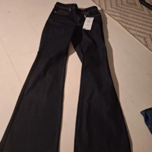 Mörkblå bootcut jeans från ONLY - Snygga mörkblå bootcut jeans från ONLY med hög midja. Perfekta för en trendig look med sin utsvängda stil. Klassisk femficksdesign och knappgylf. Passar utmärkt till både vardag och festliga tillfällen. storlek S i midjan och 30 i längden. Nypris är 459 kr