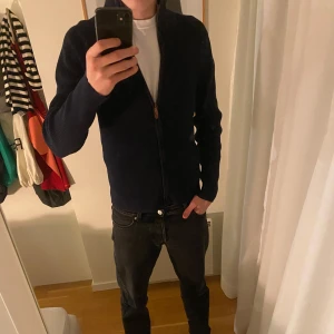 Mörkblå kofta med dragkedja - Säljer en stilren mörkblå kofta med dragkedja framtill. Perfekt för kyligare dagar och kan enkelt matchas med olika outfits. Koftan har långa ärmar och en bekväm passform.