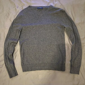 Grå tröja från Jack & Jones - Säljer en stilren grå tröja från Jack & Jones i storlek XS. Tröjan har en v-ringad design och är tillverkad i ett mjukt material som passar perfekt för kyligare dagar. Har ni frågor är det bara fråga!