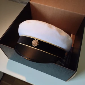 Studentmössa  - Säljer studentmössa i storlek 55 eller som har en omkrets på 55cm. Har inga fläckar eller namn skrivna men har ett litet pen streck på insidan ( bild 4 ). Medföljande påse och kartong finns också, mössan är ifrån C.L.SEIFERT 