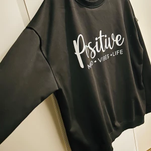 Svart tröja med text - Säljer en svart tröja i storlek 1XL med texten 'Positive Mind Vibes Life' tryckt på framsidan. Tröjan har en klassisk rund hals och långa ärmar, perfekt för en avslappnad stil. Materialet känns mjukt och bekvämt, idealiskt för både vardag och mysiga stunder.