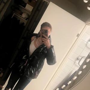 Tommy hilfiger jacka - Säljer en svart glansig pufferjacka i nyskick💕 Den har en cool, quiltad design med dragkedja och praktiska fickor💕 Perfekt för vintern med sin varma och stiliga look. Jackan har långa ärmar och en skön huva för extra skydd mot kylan💕 märket är Tommy hilfiger💕