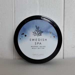 Swedish Spa Whipped Waves Body Butter från Oriflame - Säljer en burk Swedish Spa Whipped Waves Body Butter från Oriflame. Denna kroppssmör är perfekt för att återfukta och mjukgöra huden. Burken innehåller 200 ml och har en elegant design med en svart lock och en vit/blå etikett med en fin illustration. Perfekt för att skämma bort dig själv eller som en present!