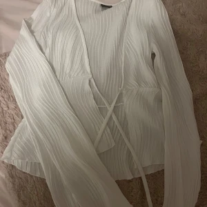 Vit ribbad topp med knytning - Säljer en superfin vit ribbad topp i storlek xs från Gina tricot. Den har långa ärmar och en söt knytning framtill som ger en fin detalj. Perfekt för både vardag och fest! Toppen är i nyskick och väldigt bekväm att ha på sig. Passar perfekt till jeans eller. nästan helt oanvänd ändats testad!💞