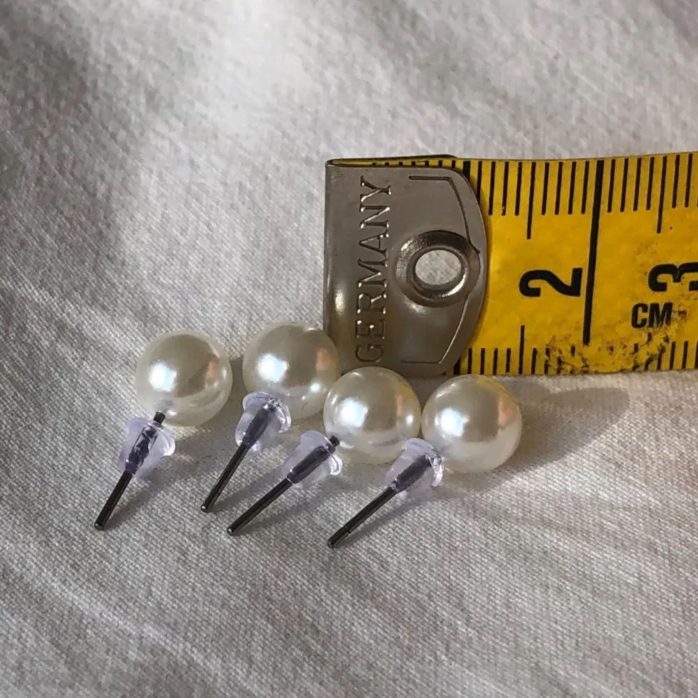 Två par krämvita pärlörhängen i klassisk fin modell. Nyskick och aldrig använda. Storlek ca 0,7cm. Vikt ca 1g.. Asusteet.
