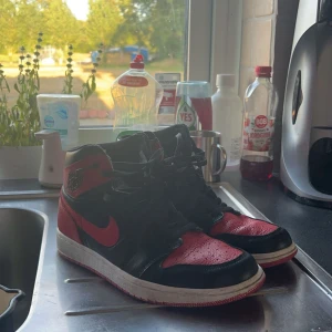 Svarta och röda Nike Air Jordans - Säljer ett par svarta och röda Nike Air Jordans. Skorna är i välanvänt skick men fortfarande snygga och bekväma. Perfekta för både vardag och träning. De har snörning och en klassisk design med Nike-loggan på sidan.