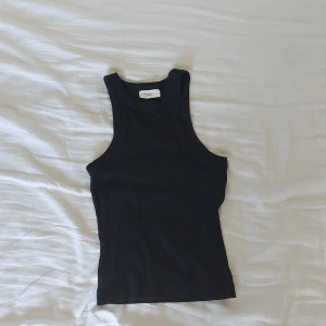 Svart ribbad linnetopp från Gina Tricot - Säljer en svart ribbad linnetopp från Gina Tricot i storlek XS. Toppen är ärmlös och har en tight passform, perfekt för sommaren. Den är enkel och stilren, vilket gör den lätt att matcha med olika outfits. Använd men i bra skick.