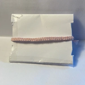 Armband  - Handgjort armband i bomullsgarn, man kan ändra storleken 15-22 cm, 0,5 cm brett. Armbandet är ljusrosa