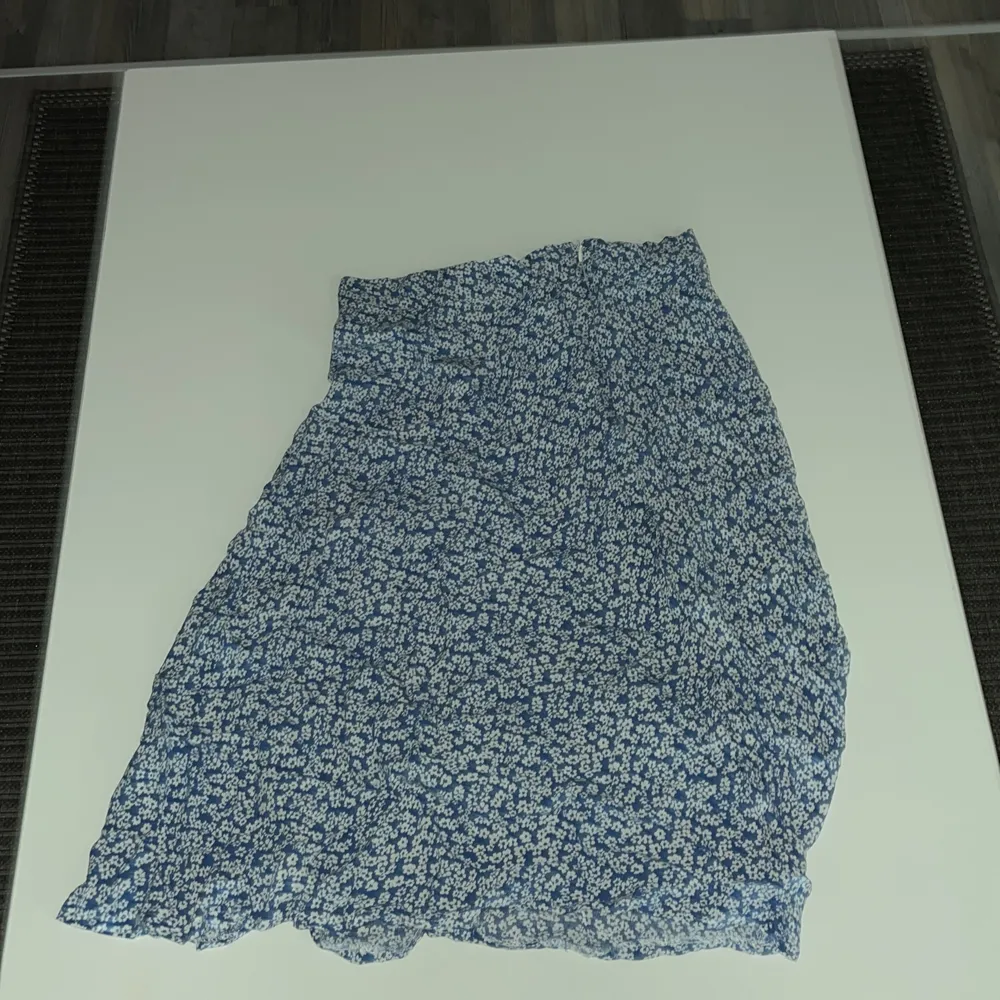 En marinblå kjol med vita blommor på den är i storlek S. Kjolar.