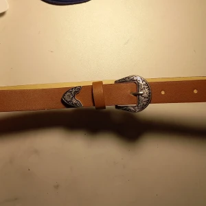 Brunt bälte - Jätte fint bälte! Den är 82 cm lång och kan stylas på många sätt. Bältet har jätte fina mönster på metallen. Jag säljer den då jag har bytt stil.. Om den inte riktigt passar din stil heller kan du alltid ge den till någon annan eller tipsa!