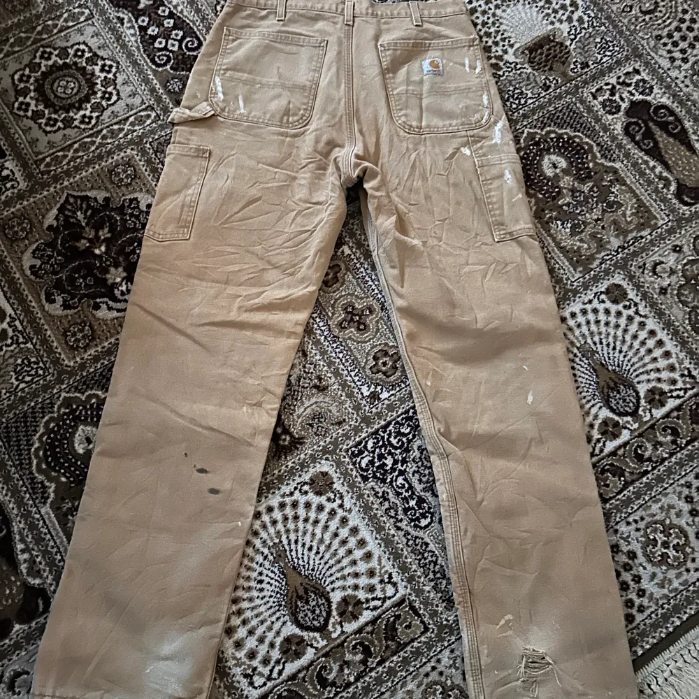 riktigt snygga carhartt carpenter byxor i en beige färg. sitter väligt bra och ör raka. byxorna har ganska mycket färg fläckar på sig som enligt mig är snyggt samt lite slitna här och där. söker byten eller bud på dessa. Jeans & Byxor.