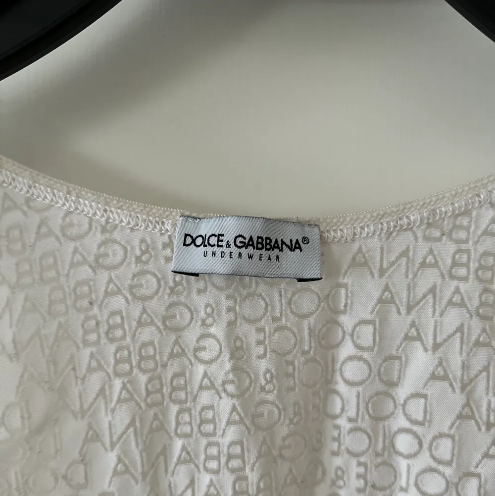 Vitt linne från Dolce & Gabbana. Står ”underwear” men har använt det som vanligt linne, det funkar som båda. Lite genomskinligt. Stretchigt. Dolce & Gabbana mönster över hela linnet. Använt en gång. Köpt på Humana. Står ingen storlek men passar XS-M. . Toppar.