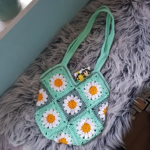 Virkad Väska - Granny square väska gjord i bomull och akrylgarn med blandade nyanser av grönt💚 Väskan är ca 28 cm i bredd och ca 28 cm i längd. Räknar man med axelremmen är väskan 52 cm i längd totalt🍀 (Lång axelremm)Frakt ej inräknad i priset🌸