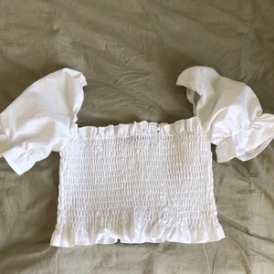 Vit topp - Vit, jättesöt, ribbad/krusad topp med puffiga ärmar. Storlek S men skulle säga att den sitter minst lika bra på XS! Fint skick! Köpare står för frakt och kom gärna privat vid eventuella frågor🥰
