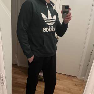 Grön adidas hoodie. Använd, små skavanker på trycket (se bild 3). Nypris ca: 700:- OBS: kläderna är skrynkliga då de legat nerpackade.