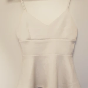 Somrigt linne - Vitt sommalinne med volang, strl XS. Använt men inga synliga fläckar. Scuba-liknande material.  Pris exkl frakt, kan hämtas på Lilla Essingen alt mötas upp på Fridhemsplan.
