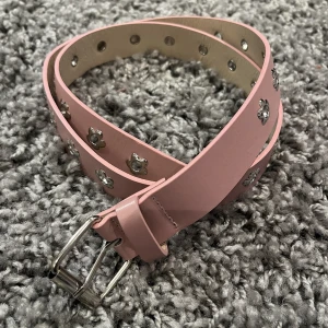 Gulligt rosa skärp med blommor - Rosa skärp med silvriga blommor som hål. Aldrig använt.