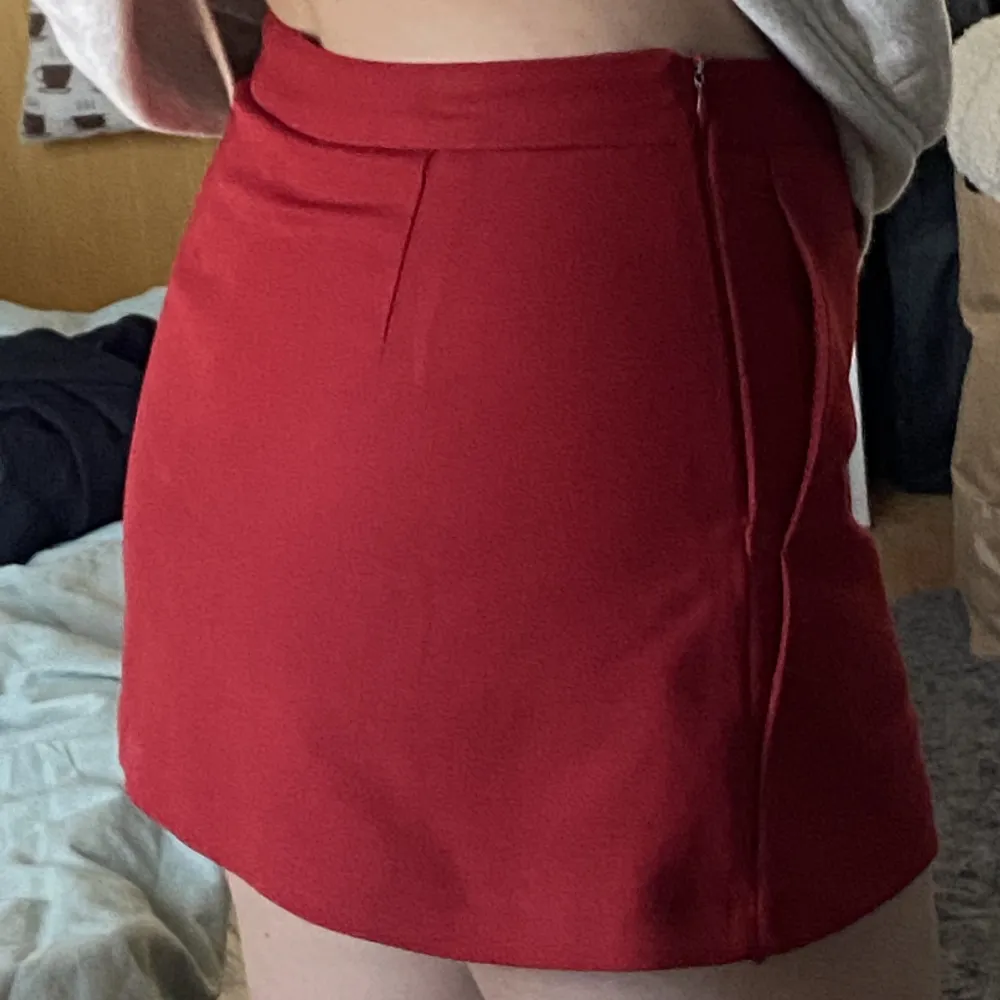 En röd kort kjol men shorts insydda. Skön men väldigt kort. Jag är 163 cm lång. Fotvård framfickor. Dragkedja på sidan. . Kjolar.