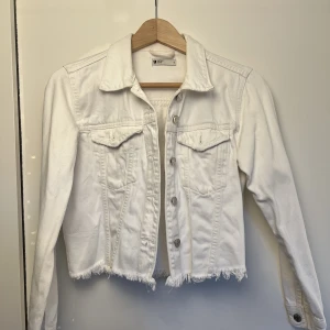 Jeansjacka - En lätt och fin jeansjacka perfekt nu till våren och sommaren. Använd  en del gånger. Den är ganska kort i modellen. Den har även en liten fläck som tyvärr inte gått bort! Annars är den i bra skick för att vara använd.
