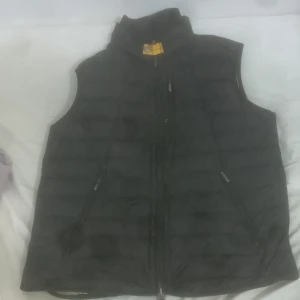 Parajumper väst  - Jag säljer en svart parajumper väst för 950 kr och ny pris ligger på 3-4 tusen. Storlek L men passar även på storlek M. "Min kamera är lite sprucken btw". Vita fläcken är bara lite färg och inte ett håll.