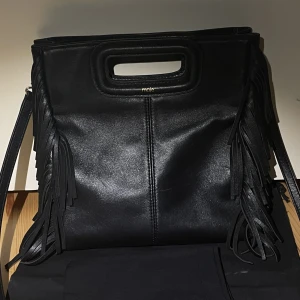 Maje väska  - Jättefin Svart Maje väska köpt för 2500kr som jag säljer för 1900kr. Den kommer med två dustbags, den är i väldigt fint skick inga skador💕