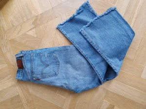 Högmidjade Levis jeans - Så snygga Levis till vår/sommar. W29. Höga i midjan, kortare benlängd, något utsvängda & fransiga i benslutet. En deffekt kch det ör bruna lappen bak på byxan som blivit skrynklig lite hård.  Annars för övrigt, Jättesnygg!