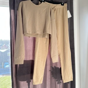 Mjukisset  - Beige SOC Mjukisset i strl M/L i tröja och strl M i byxor. Helt oanvänt! Säljs för 299kr för byxorna och 249kr för tröjan. Tröjan och byxorna är inte exakt likadan färg den andra är lite ljusare än den andra