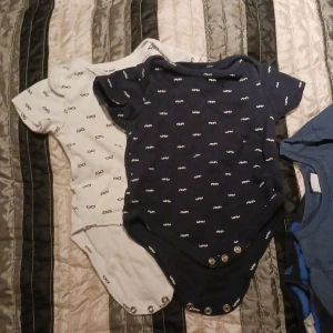 2 bodies barn - 1st kortärmad vit med motiv, 1st mörkblå med motiv. Storlek 68. Använt skick.