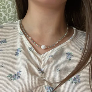 Halsband  - Halsband med en vit pärla i mitten. Färgerna guld, turkos och lila. Ca 45 cm längd. Har gjort själv. Ej andvänt frakten ej korrekt hälften så billig ungefär 