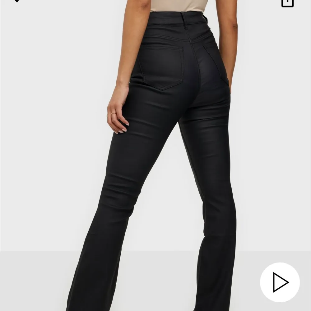 Svarta ”coated” byxor med utsvängda ben från Nelly. Storlek 32. Aldrig använda, bara provade💘. Jeans & Byxor.