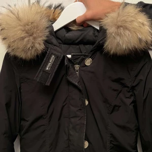 Woolrich jacka  - Storlek Xs. Färg Svart.  I bra skick och super fin päls, går att kemtvätta jackan om man tar av pälsen. 