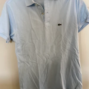 Ljusblå lacoste piké  - Ljusblå lacoste pike Storlek: 176cm