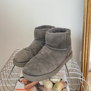 UGGS mini grå  - Storlek: 38, men funkar för mig som har 39 då ullet är lite nedgånget  Skick: som ett par använda Uggs ser ut, tyget har skrymplat ihop lite vid tårna, lite missfärgning men de har ändå hållit färgen & kvalitén