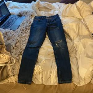 Ett par mörkblåa jeans från lager 157, lite sönder på knät men det är en ganska skön detalj