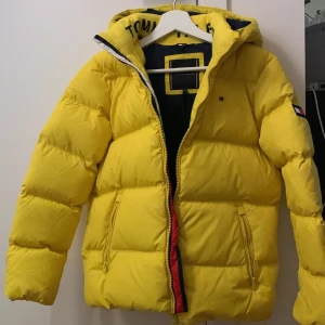 NY Tommy Hilfiger dunjacka stl 152 - En sprillans ny dunjacka från Tommy Hilfiger i gult, snygga detaljer. Essential down jacket - valley yellow stl 152. 10/10 aldrig använd.