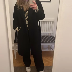 Svart kappa  - Svart simpel kappa med knytband och sidofickor från Vero Moda. 