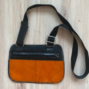 Väska - Fin, liten väska med justeringsbar band och orange ”päls” på framsidan! Fint skick! ❤️❤️❤️