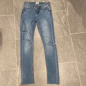 Ett par blåa skinny jeans från lager 157 i strl Xss. Har två hål på högra benet och ett hål på de vänstra 