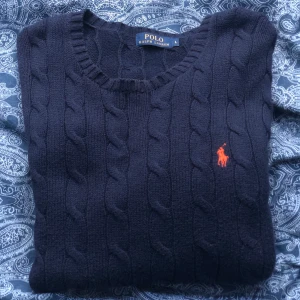 Ralph Lauren tröja - Mörkblå kabelstickad tröja från Polo Ralph Lauren (äkta såklart) i storlek L. På bilderna har ja stoppat in tröjan då den är ganska lång. Säljer den för 170kr plus frakt som ligger på 66kr. Bara att höra av sig om man har frågor🫶🏻