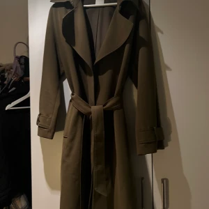 Trenchcoat från H&M  - Säljer denna jättefina gröna trenchcoat från H&M.  Står ingen storlek i den men skulle säga att de är i storlek M.  Frakt tillkommer på 59kr annars kan den hämtas i nacka