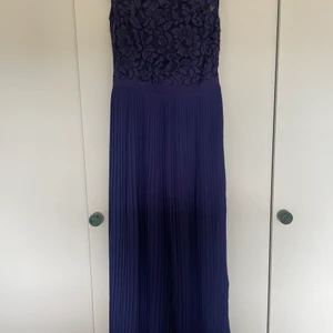 NY balklänning - OANVÄND mörkblå finklänning från H&M. Liv i spets och plisserad kjol i chiffong. Satinfodrad liv med stödskenor + dold dragkedja i sidan. Finns i Sollentuna, kan mötas upp om det inte är för långt bort. 