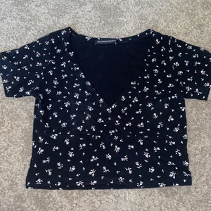 Brandy Melville tröja  - Säljer denna underbart fina tröjan från brandy melville då den inte används längre. Köpt 2021 och har använt den några gånger. Den är sparsamt använd och inga tecken på att den är använd syns. Den är mörkblå och passar bra till vitt då de vita blommorna på komplimenterar det. 