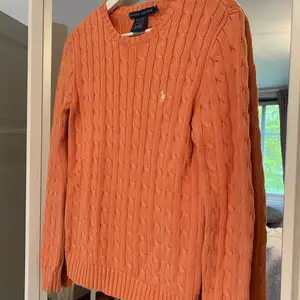 En kabelstickad tröja från Ralph lauren i en magisk orange färg. Knappt använd så i nyskick. 