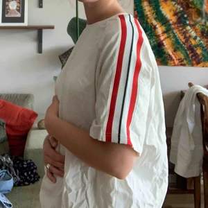 Weekday T-shirt  - Vit T-shirt med ränder längs ärmarna. Priset+frakt